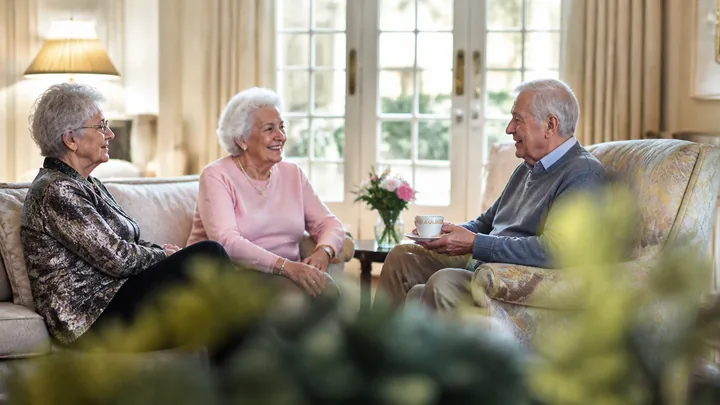 Two women and a man relaxing together on a couch with coffee