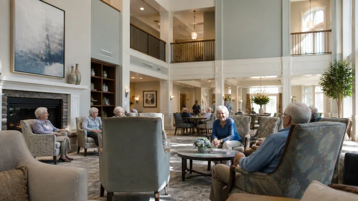 Residents gathered in a two-story lounge with blue-grey walls