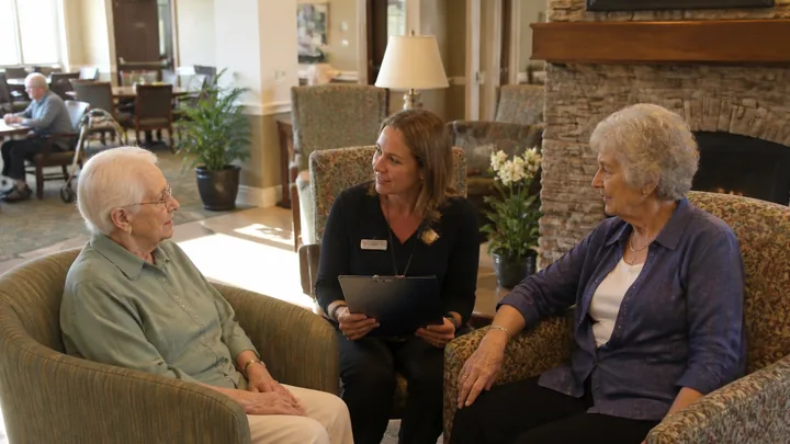 A staff member with a clipboard talking with two residents