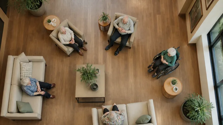 Overhead view of four residents seated together in a wood-floored lounge